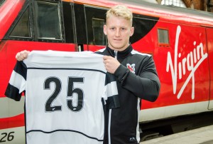 Tom Portas stands with a number 25 shirt in front of a Virgin train