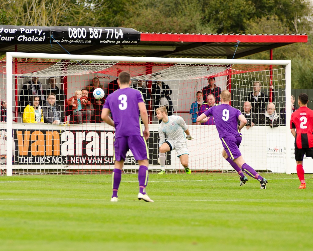 Josh's free kick is on its way into the net, with Mark Beck, Jordan Watson and the Brackley keeper watching