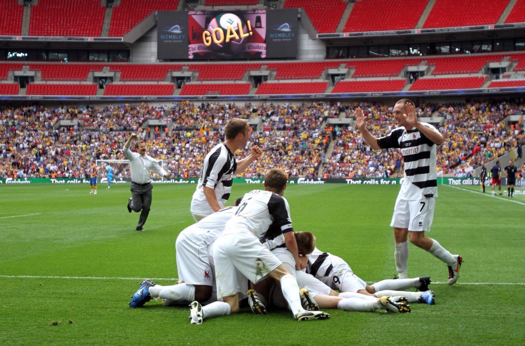 Darlington players celebrate after Chris Senior's goal plus manager Mark Cooper running on the pitch in the background left.